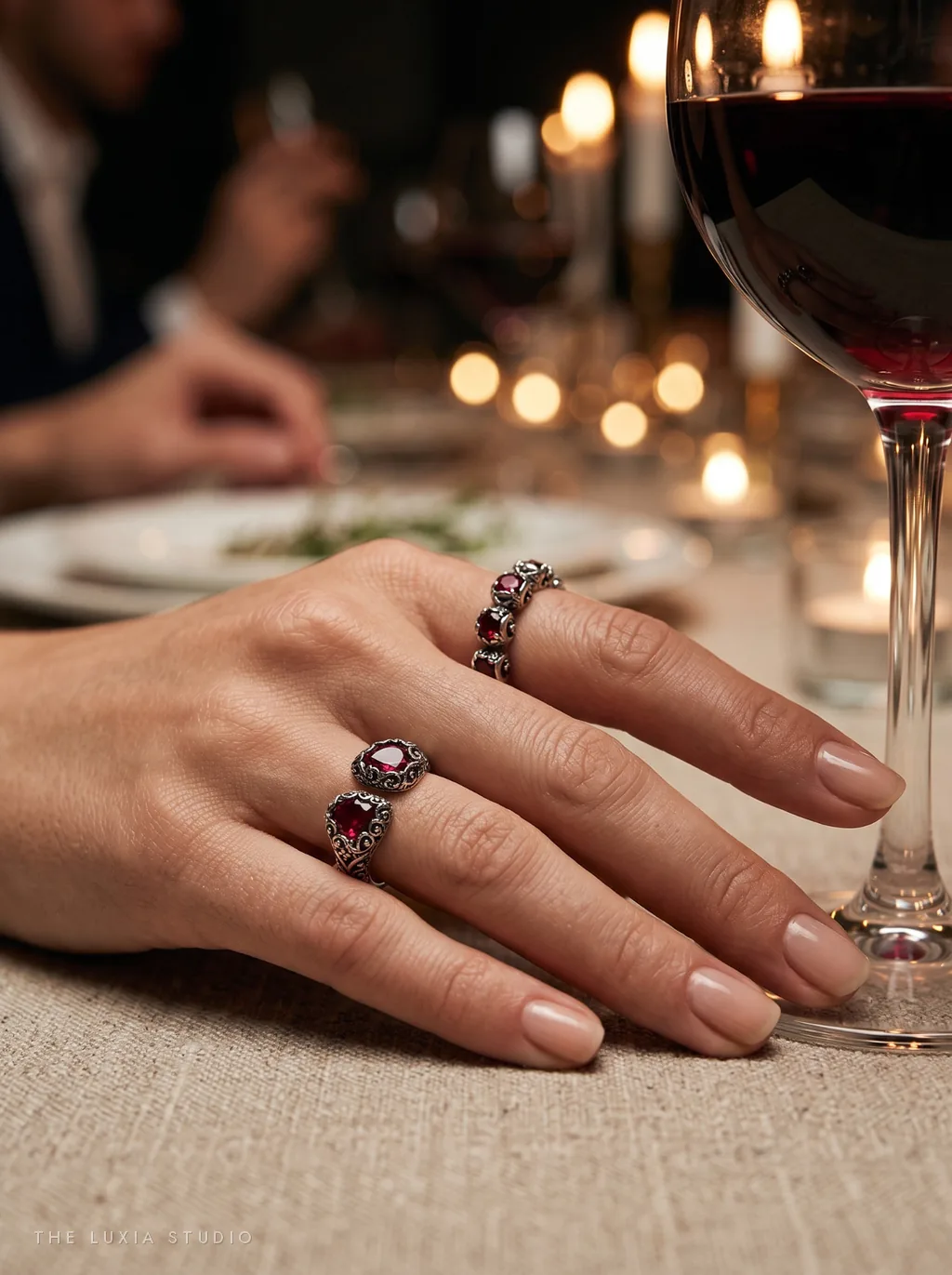 Después, ambiente: mano de modelo creada con IA con los mismos anillos junto a una copa de vino en una cena con velas