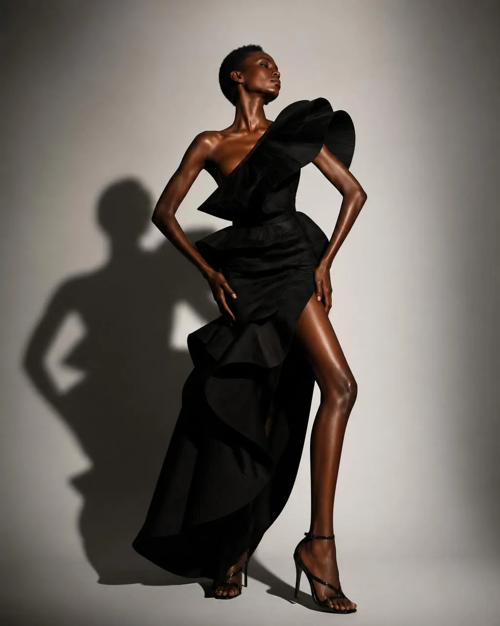 Modelo creada con IA con vestido negro asimétrico con volantes en pose de pasarela con luz de estudio